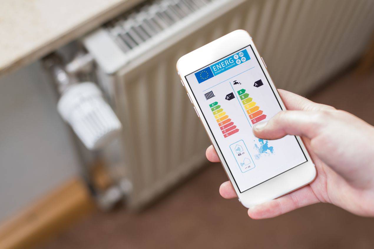 Hand mit Smartphone zeigt Energieeffizienz-App zur Kontrolle von Heizsystemen im Kontext von Heizölpreise Essen